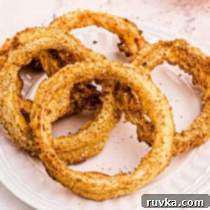 Bring Back the Crunch Air Frying Onion Rings 5 Close up on onion rings on a white plate.