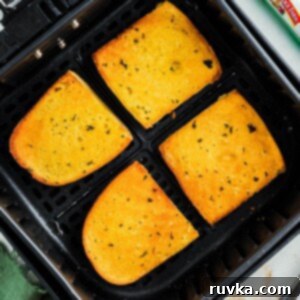 Perfect Air Fryer Frozen Garlic Bread 8 Golden crispy buttered garlic bread in the air fryer basket after being cooked.