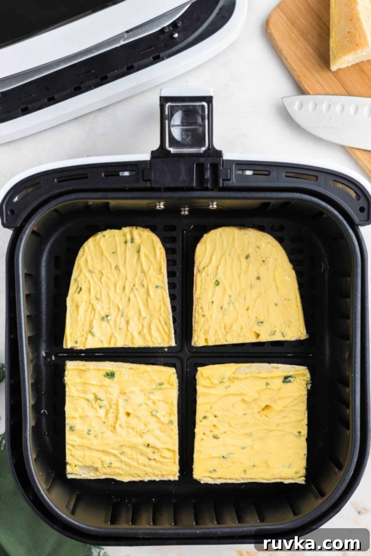 Perfect Air Fryer Frozen Garlic Bread 5 Frozen buttered and seasoned slices in an air fryer basket before being cooked.