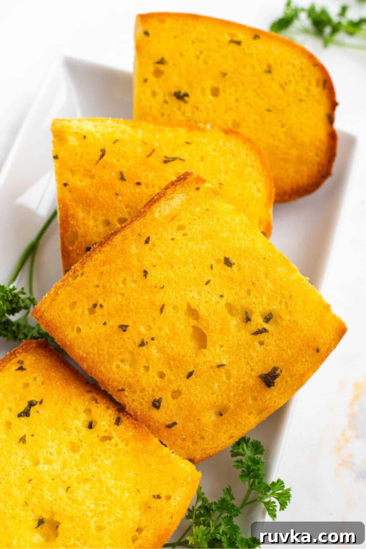 Perfect Air Fryer Frozen Garlic Bread 7 Golden crispy garlic bread toasted and stacked on a white plate.