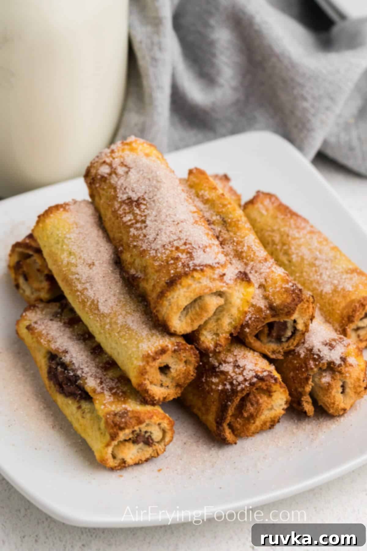 Nutella Stuffed Air Fryer French Toast Pinwheels 2 Nutella stuffed french toast roll ups made in the air fryer and served on a plate.