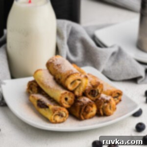 Nutella Stuffed Air Fryer French Toast Pinwheels 8 Air Fried Nutella French Toast Roll Ups on a white plate with a glass of milk in the background.
