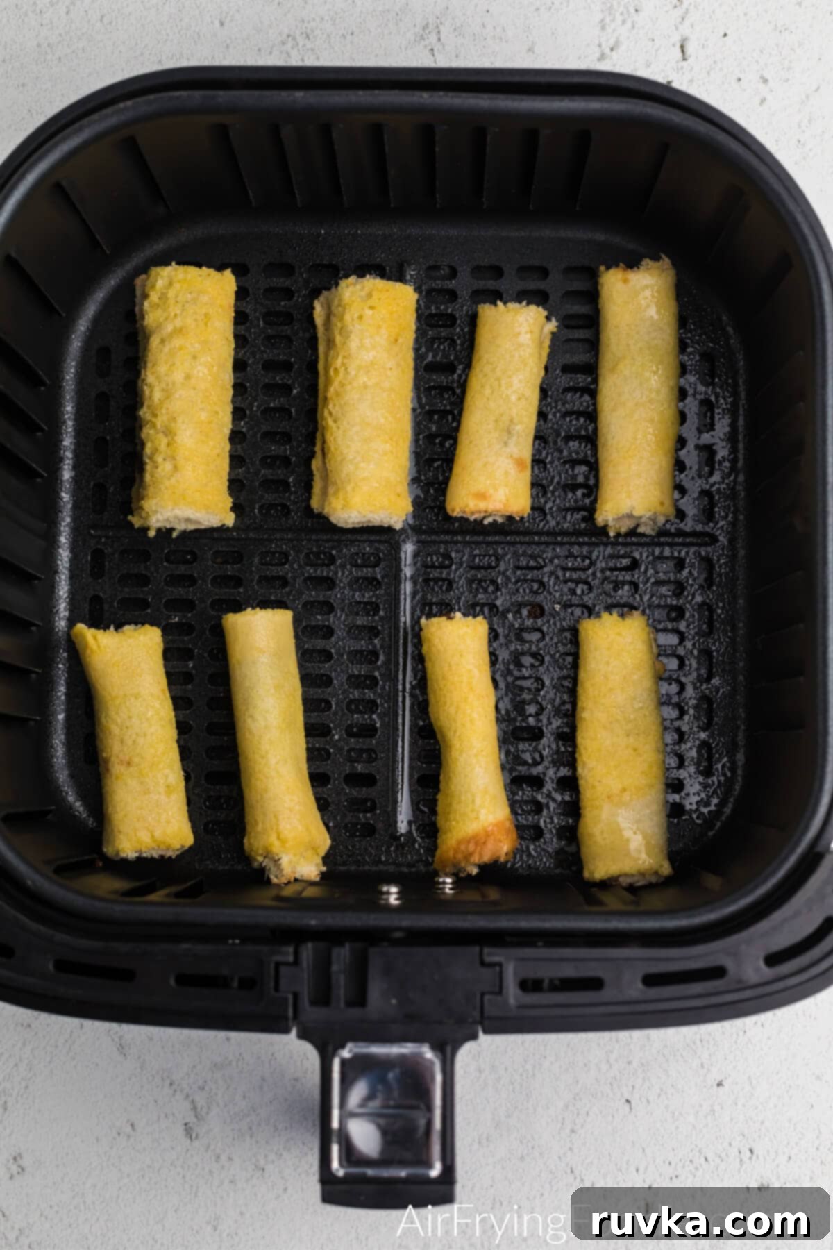 Nutella Stuffed Air Fryer French Toast Pinwheels 4 Nutella french toast roll ups in the air fryer basket ready to cook.