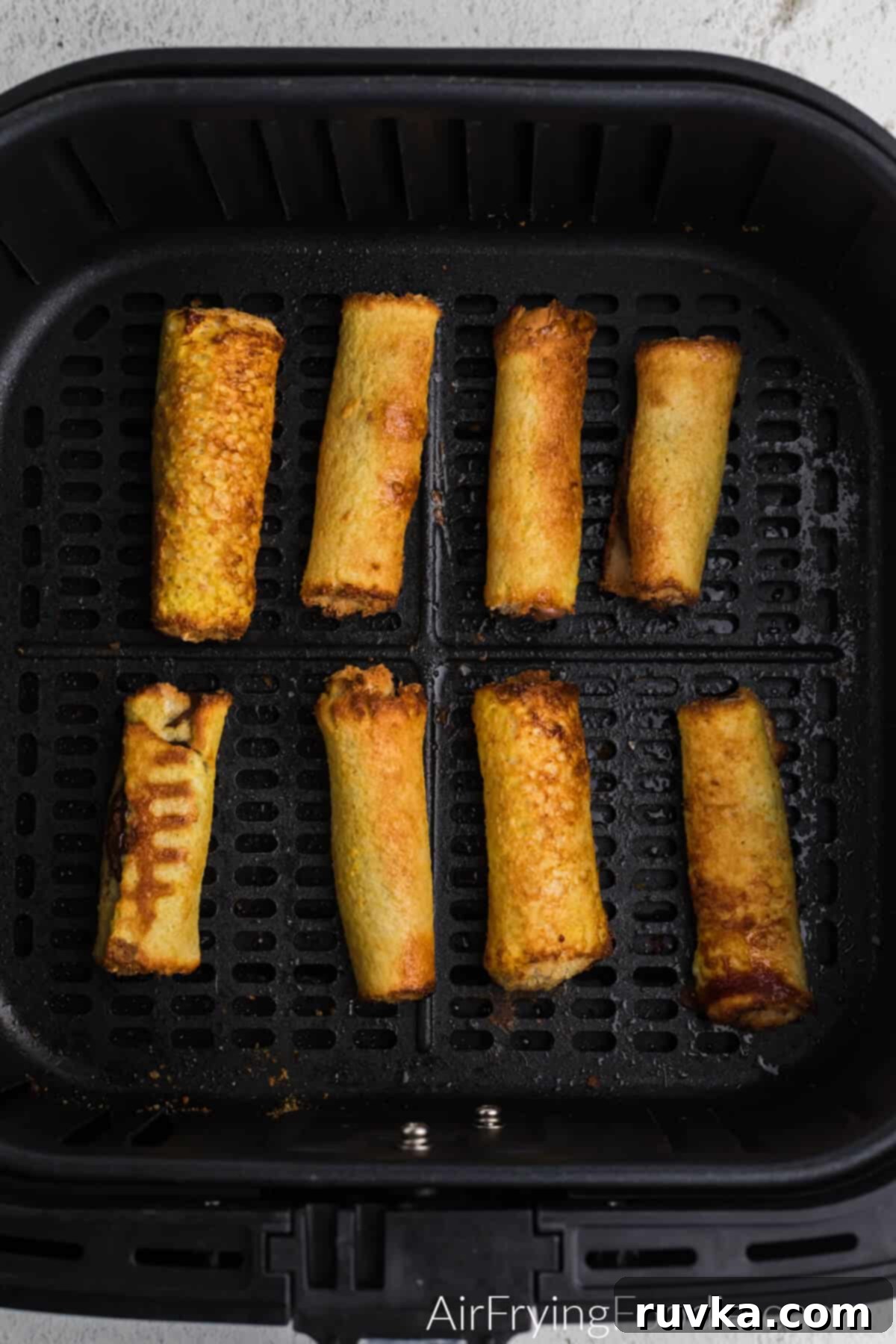 Nutella Stuffed Air Fryer French Toast Pinwheels 5 Nutella french toast roll ups in air fryer basket cooked and ready to remove and serve.