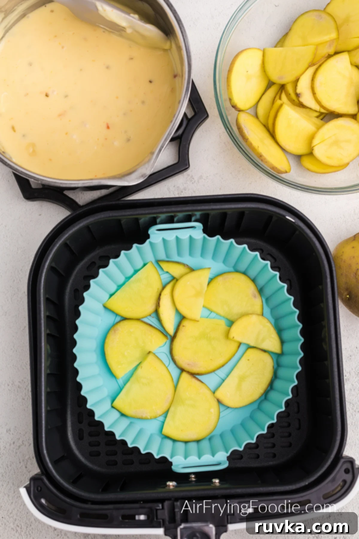 Reusable Air Fryer Silicone Baskets 3 Layer of sliced potatoes in the bottom of a silicone dish in the basket of the air fryer.