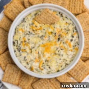 Easy Air Fryer Artichoke Spinach Dip 6 Air fryer artichoke spinach dip in a dish surrounded by Triscuit chips for dipping.