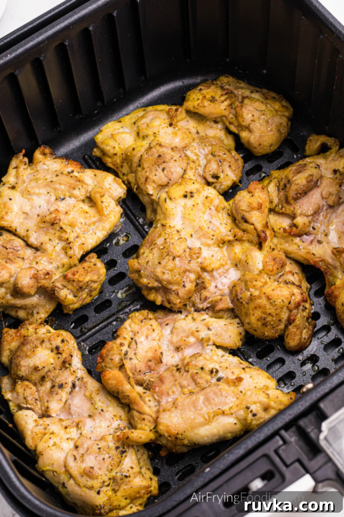 Sizzle into the New Year: 15 Air Fryer Recipes to Revolutionize Your Cooking 3 Seasoned lemon pepper chicken thighs in the basket of the air fryer, fully cooked and ready to serve.