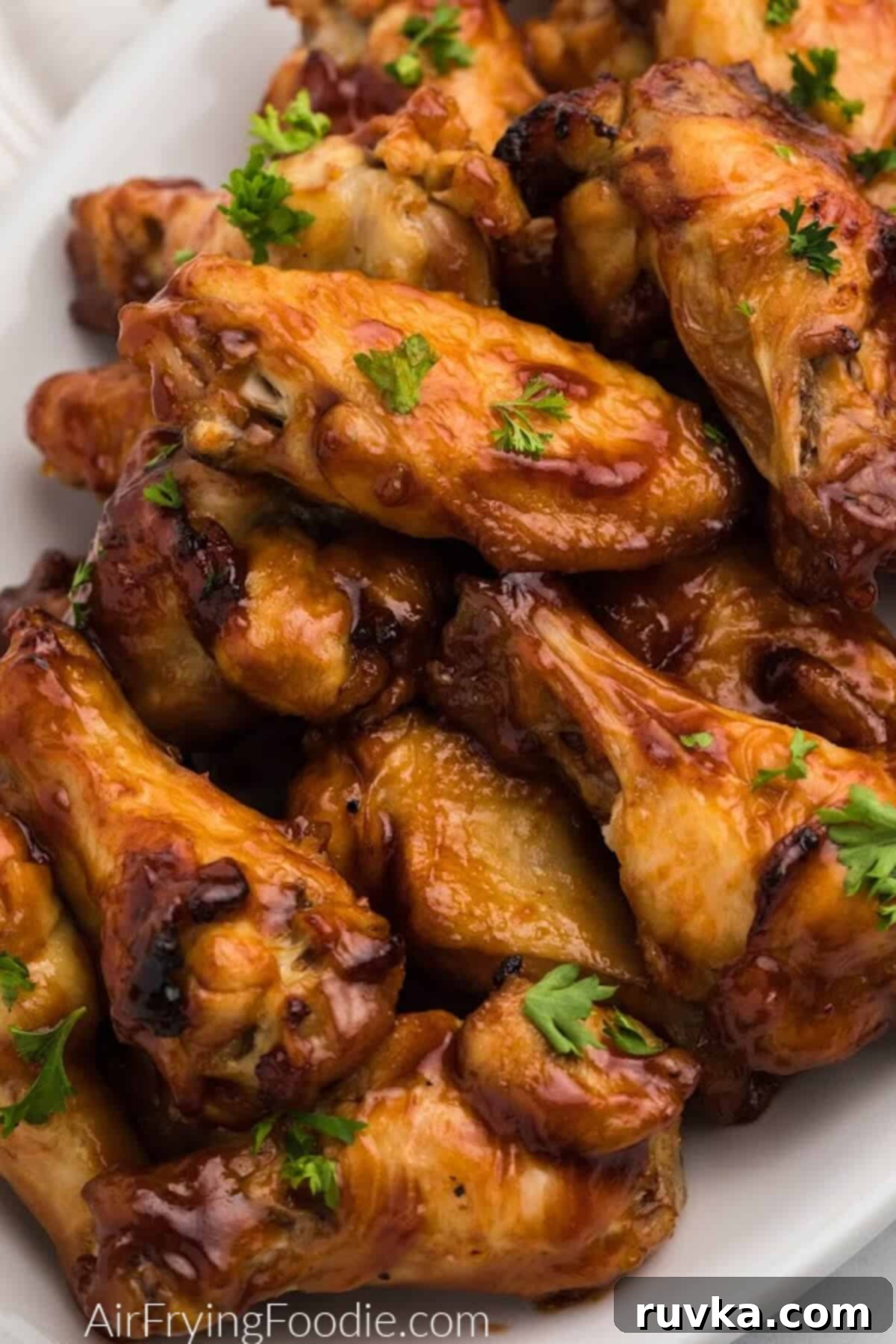 Sizzle into the New Year: 15 Air Fryer Recipes to Revolutionize Your Cooking 10 BBQ chicken wings made in the air fryer and served on a white platter.