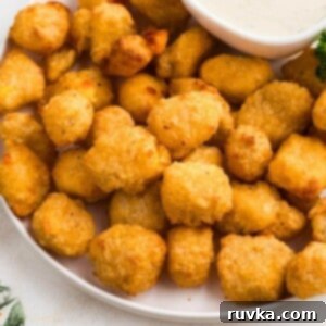 Crispy Air Fryer Frozen Cheese Curds 7 Golden brown breaded cheese curds stacked on a white plate with ranch dressing dip.