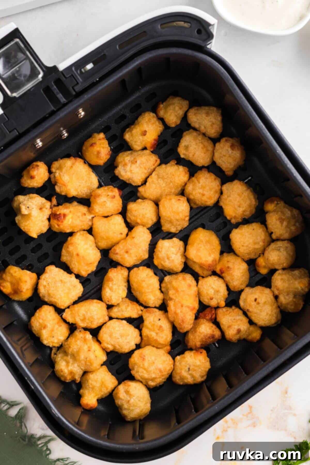 Crispy Air Fryer Frozen Cheese Curds 5 Golden brown breaded cheese curds in the air fryer basket after being cooked to perfection.