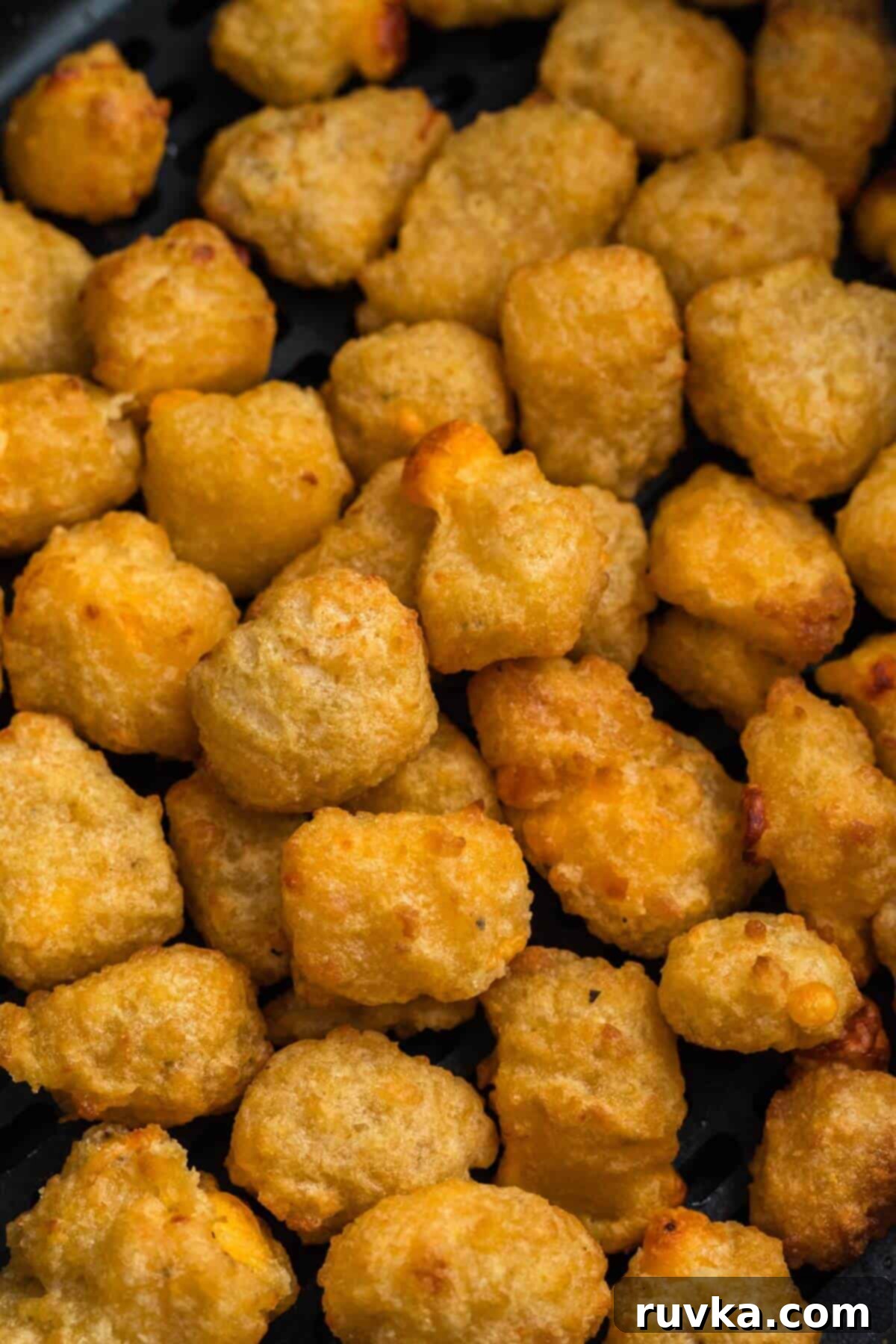 Crispy Air Fryer Frozen Cheese Curds 6 A close-up of perfectly golden brown breaded cheese curds in the air fryer basket after cooking.