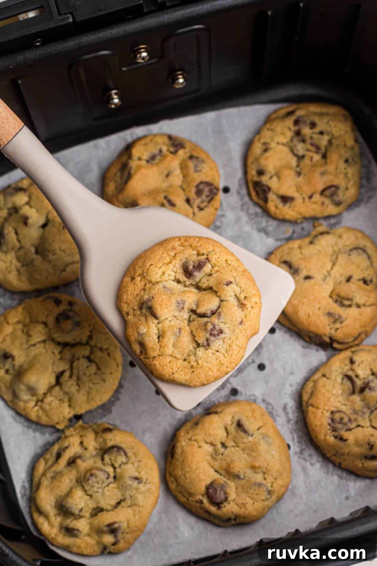 Air Frying Made Easy: Tips and Tricks for Perfect Results 2 Chocolate chip cookies being scooped up with a spatula from an air fryer basket.
