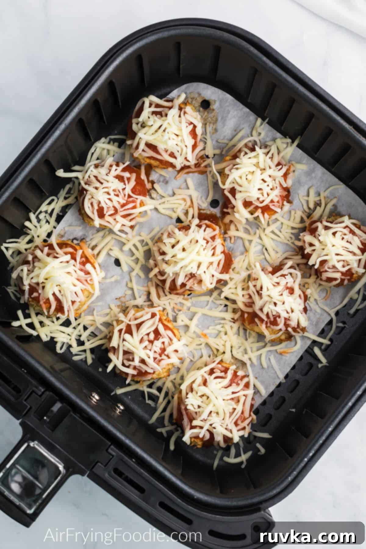 Air Frying Made Easy: Tips and Tricks for Perfect Results 5 Uncooked chicken meatball in the air fryer on top of a piece of air fryer parchment paper