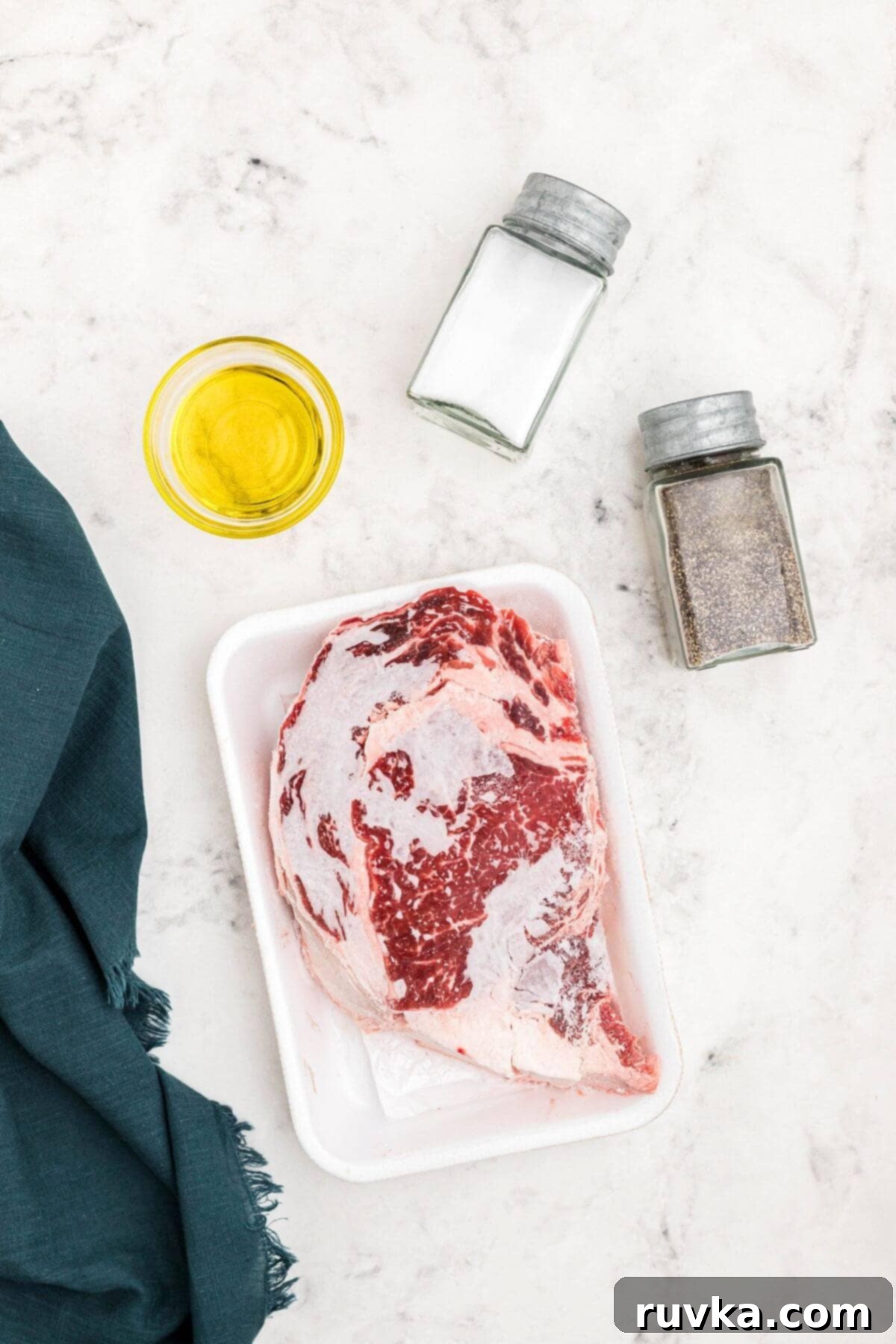 No Thaw Air Fryer Steak Perfection 3 Frozen steak with olive oil and salt and pepper on a marble table.