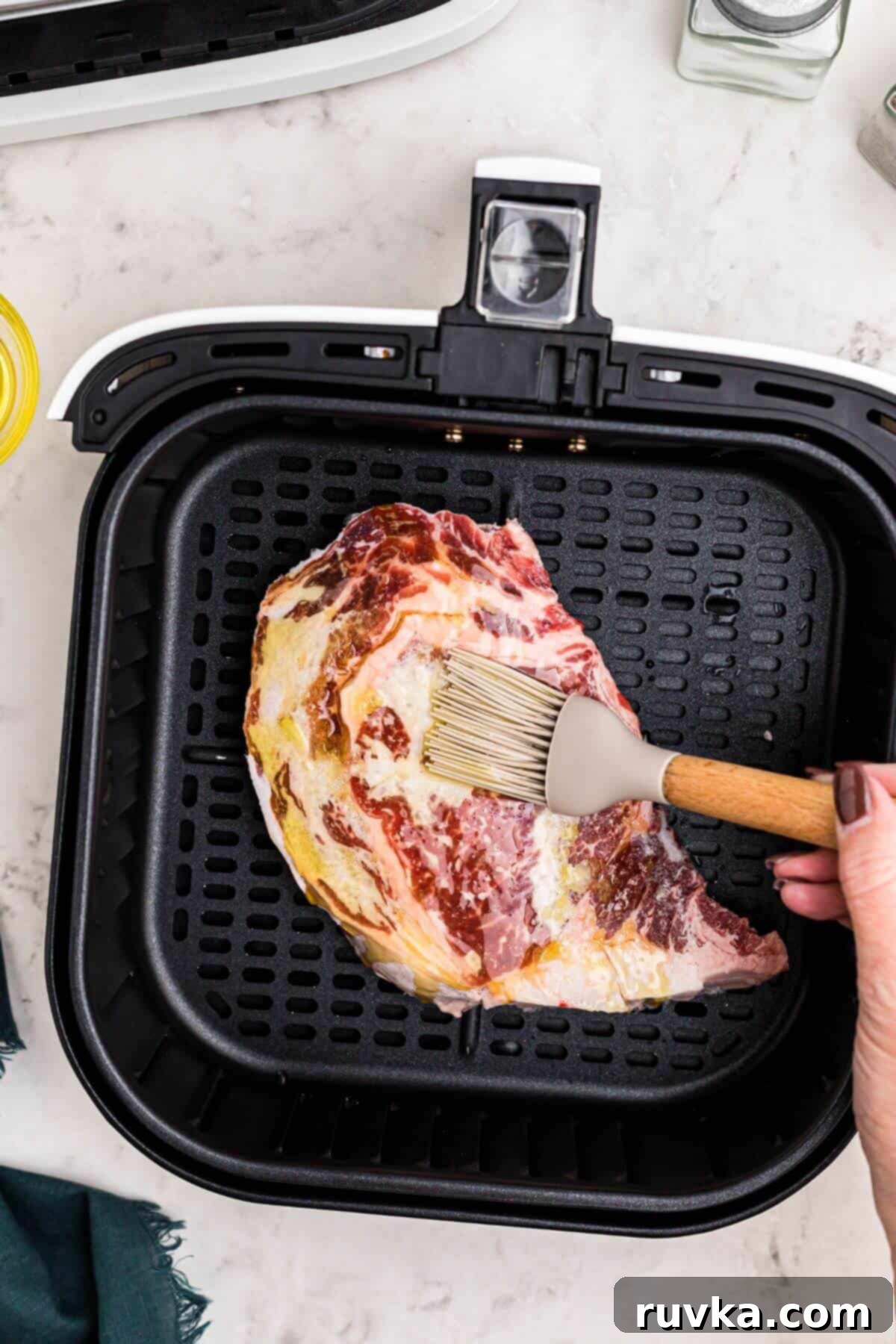 No Thaw Air Fryer Steak Perfection 4 Frozen steak being brushed with olive oil and then seasoned.