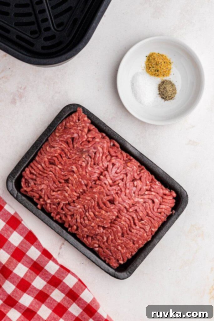 Perfect Air Fryer Burgers 3 Ground beef with salt, pepper, and garlic powder, on a white marble table.