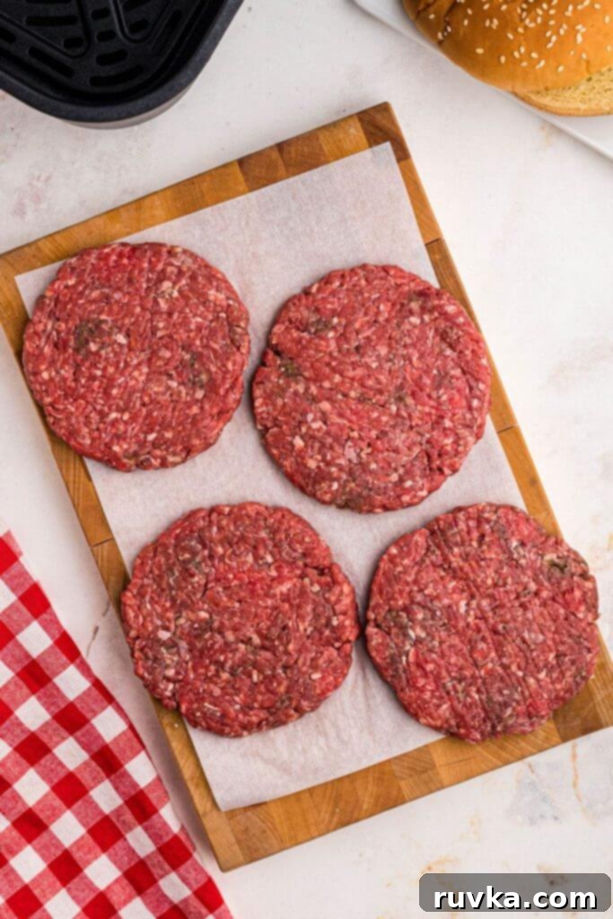 Perfect Air Fryer Burgers 4 Ground beef shaped into four patties, on a wooden cutting board.