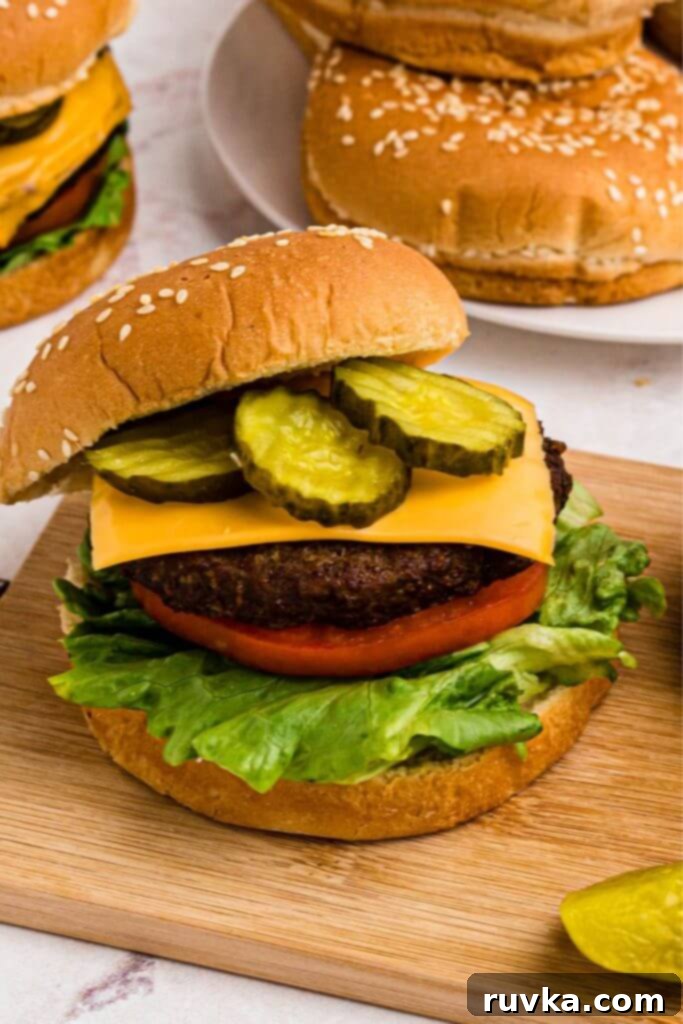 Perfect Air Fryer Burgers 6 Juicy burger patty on bun with lettuce tomato, and pickles.