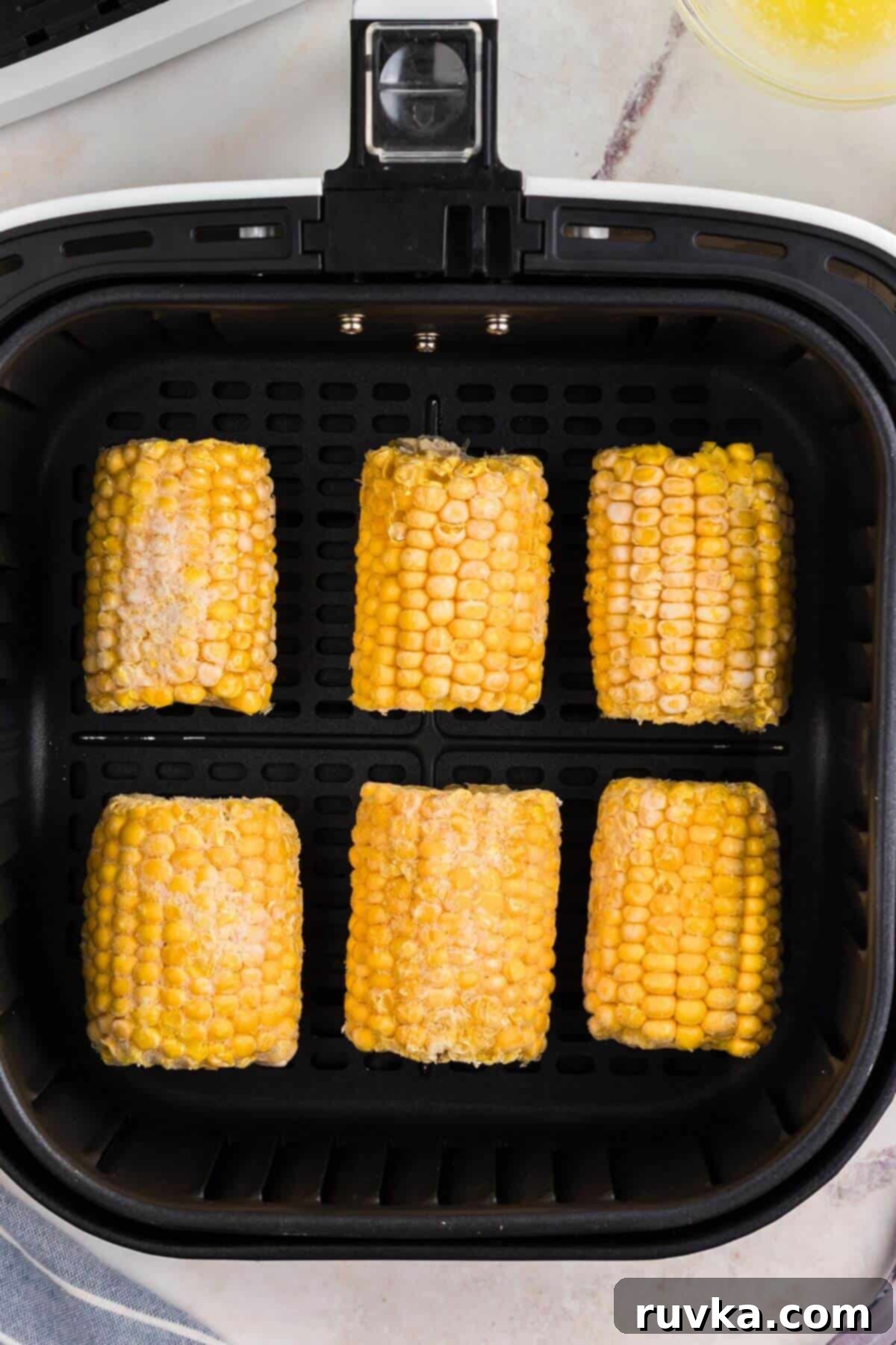 Perfect Air Fryer Frozen Corn on the Cob 4 Frozen corn on the cob in the basket.