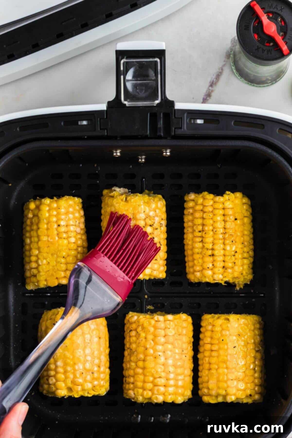 Perfect Air Fryer Frozen Corn on the Cob 5 Brushing melted butter on corn along with salt and pepper.