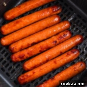 Easy Air Fryer Frozen Hot Dogs 8 Juicy plump hot dogs in the air fryer basket after being cooked.