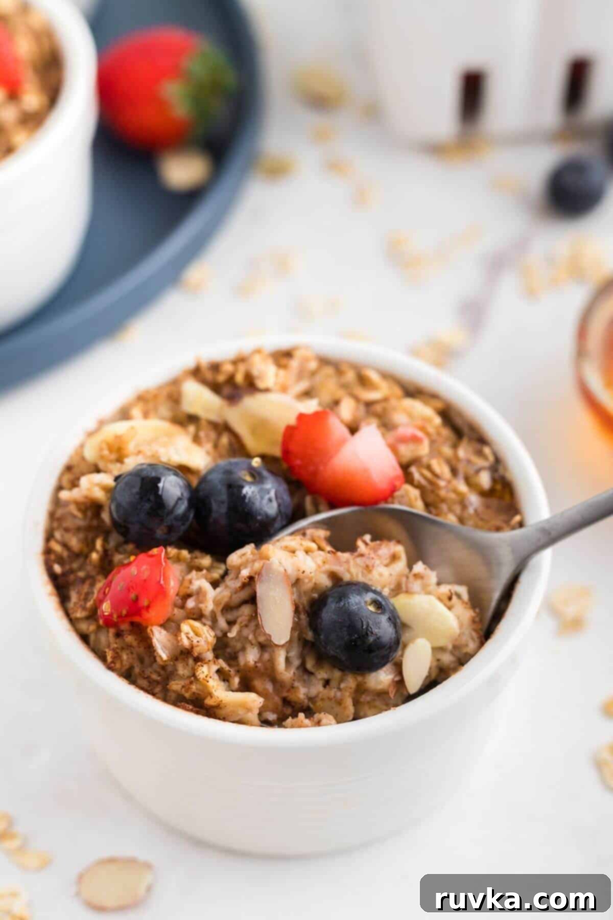Easy Air Fryer Oatmeal 7 Moist oatmeal in a white ramekin topped with fruit and slivered almonds.
