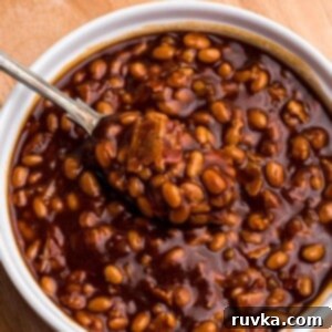 Perfect Air Fryer Baked Beans 8 Golden juicy baked beans in a white ramekin with a spoon serving.