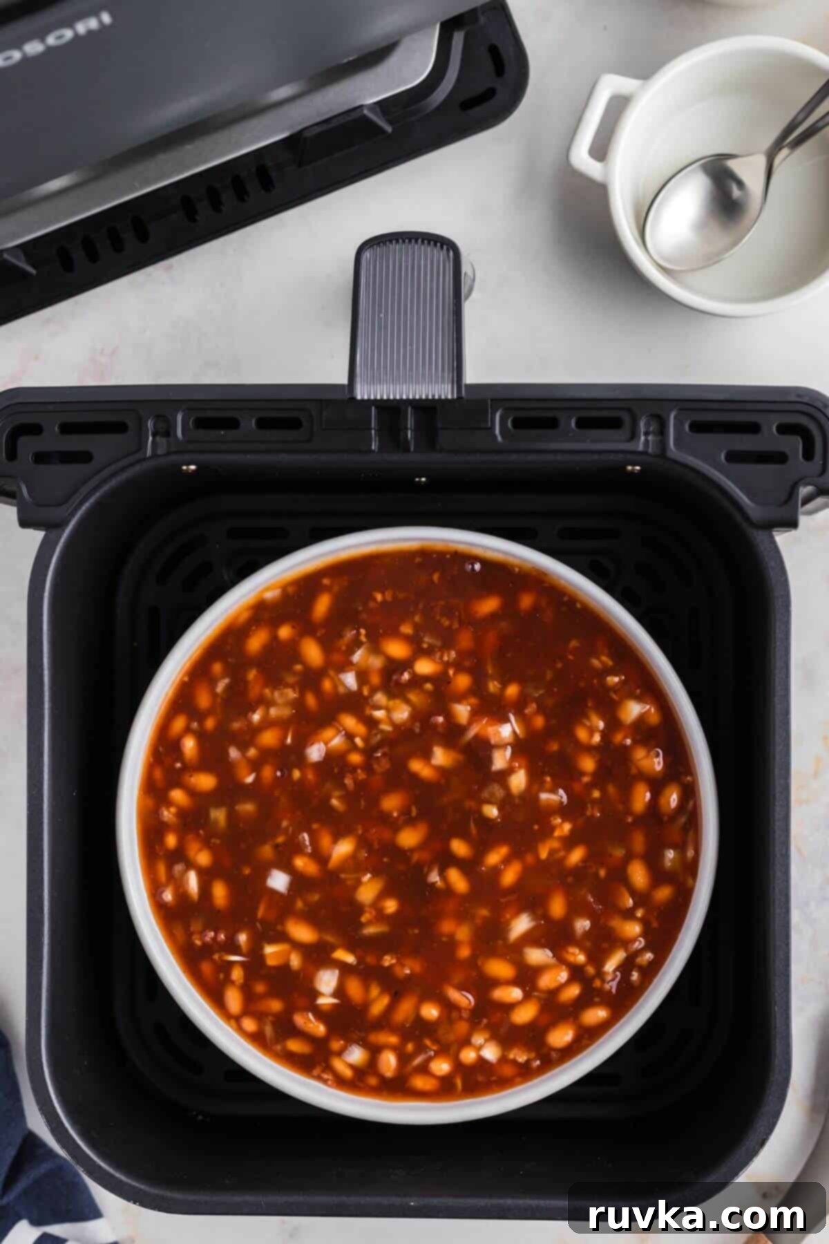 Perfect Air Fryer Baked Beans 5 Baked beans in a white ramekin in the air fryer basket.