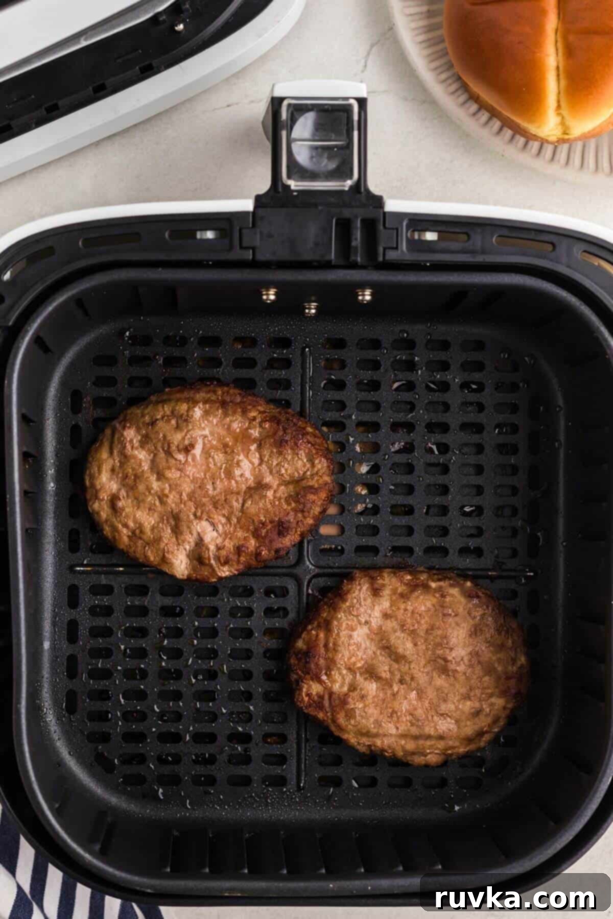 Perfect Air Fryer Frozen Turkey Burgers 5 Perfectly cooked, juicy turkey burger patties resting in the air fryer basket after cooking.