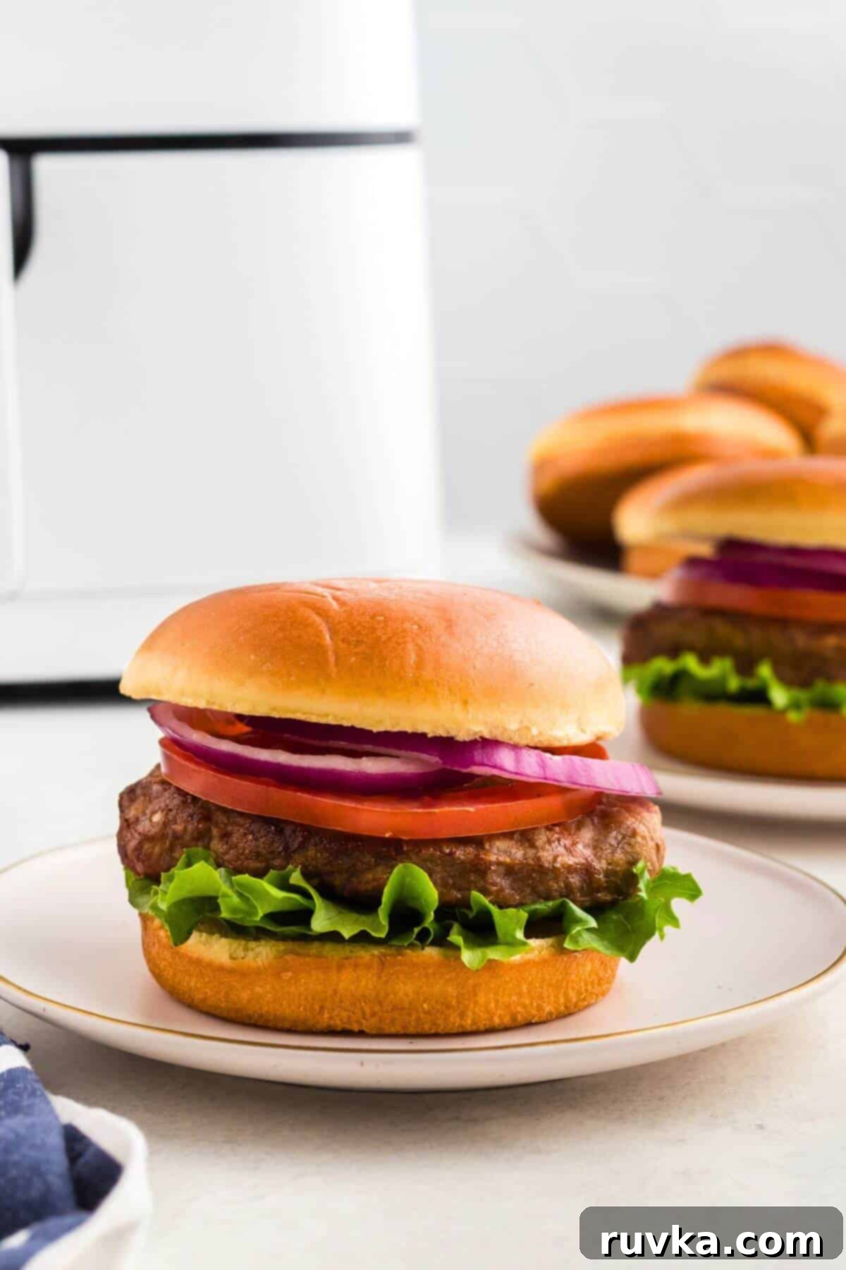 Perfect Air Fryer Frozen Turkey Burgers 7 Juicy turkey burger in a bun, topped with lettuce, tomato, and onion, served on a small white plate, ready to be enjoyed.