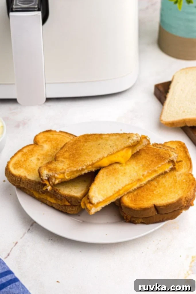 Golden and Gooey Air Fryer Grilled Cheese 2 Golden crispy grilled cheese sandwich on a white plate sliced