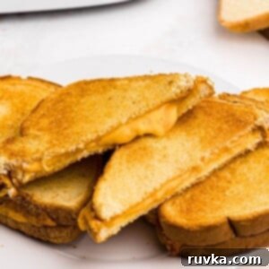 Golden and Gooey Air Fryer Grilled Cheese 8 Golden crispy grilled cheese sandwich sliced in half with melty cheese coming out