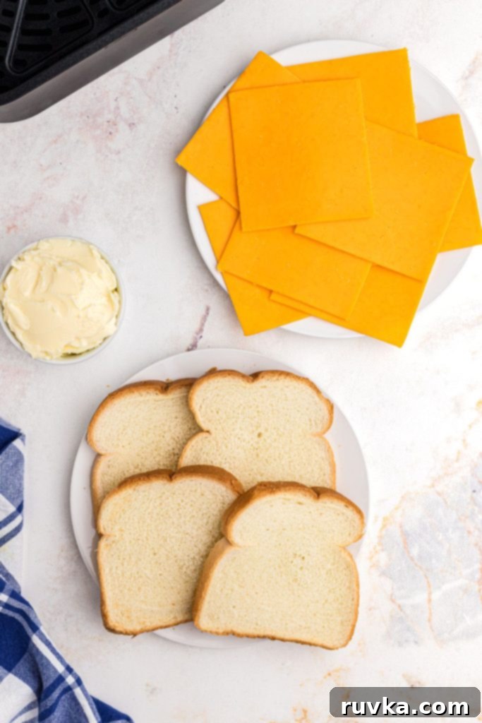 Golden and Gooey Air Fryer Grilled Cheese 3 Ingredients needed, like bread, butter, cheese, to make grilled cheese sandwiches on a marble table