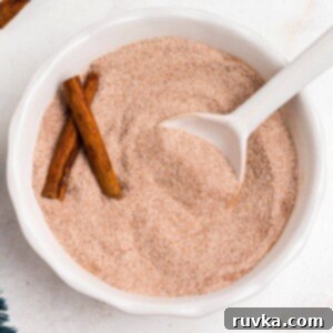 Spiced Sweetness 7 Cinnamon sugar mixed in a white bowl with a small white spoon on a marble table.