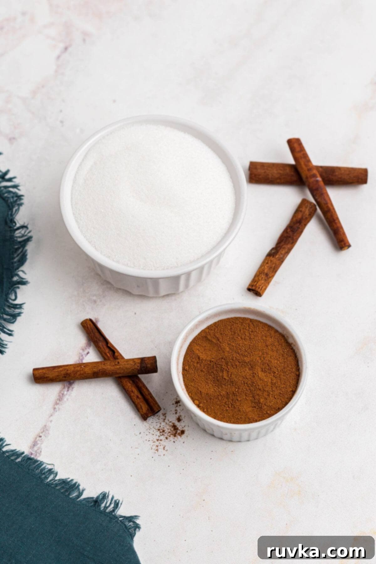 Spiced Sweetness 3 Sugar and cinnamon measured out in small white bowl on a white marble table.