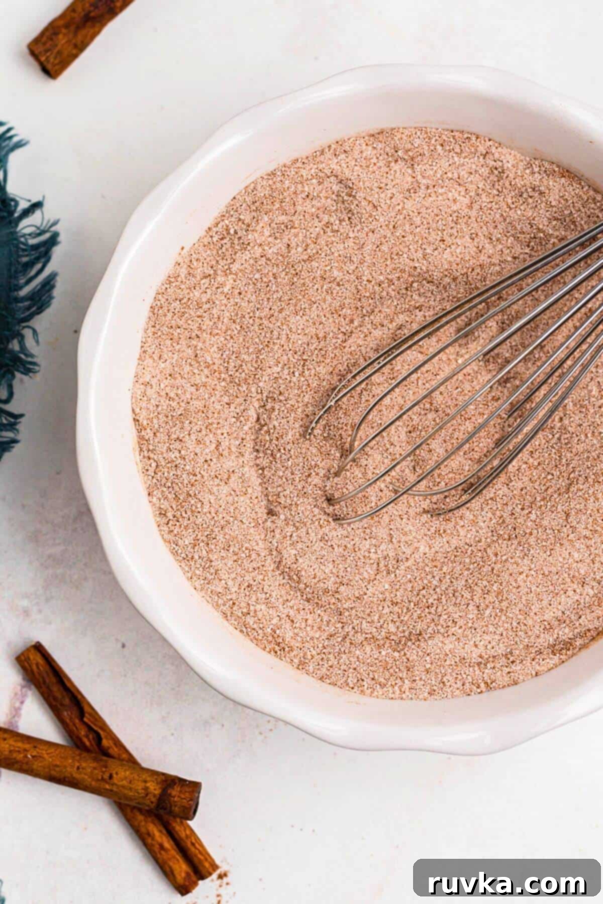 Spiced Sweetness 5 Cinnamon and sugar being mixed together with a whisk in a small white bowl.