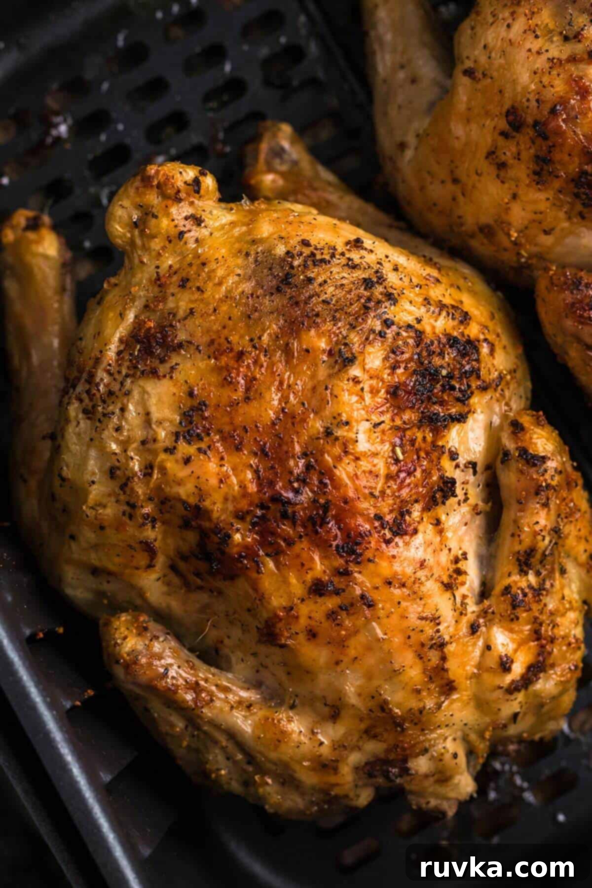 Crispy Air Fryer Cornish Game Hen 2 Golden brown juicy and crispy Cornish hen in the air fryer basket after being cooked.