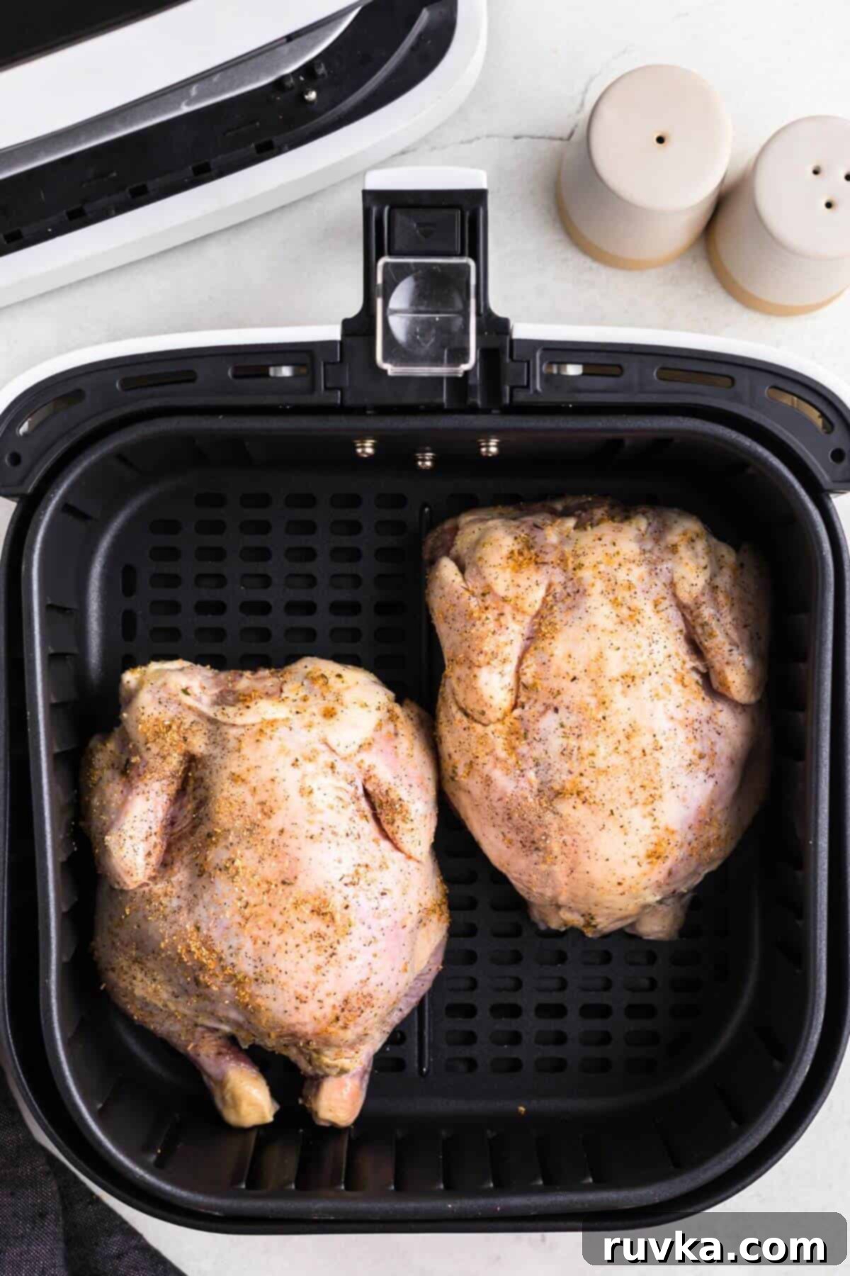 Crispy Air Fryer Cornish Game Hen 6 Seasoned uncooked Cornish hens in the air fryer basket before being cooked.