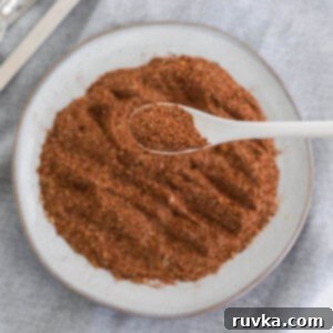 Craft Your Own Taco Spice Blend 8 Overhead photo of homemade taco seasoning on a white plate with a spoonful of the seasoning close up.