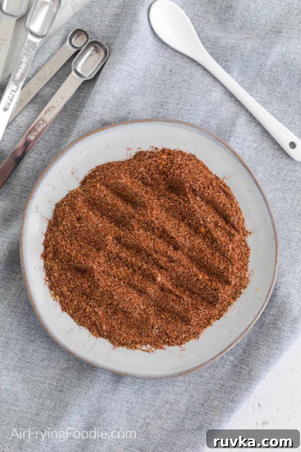 Craft Your Own Taco Spice Blend 3 Overhead photo of homemade taco seasoning on a plate with measuring spoons and a serving spoon.