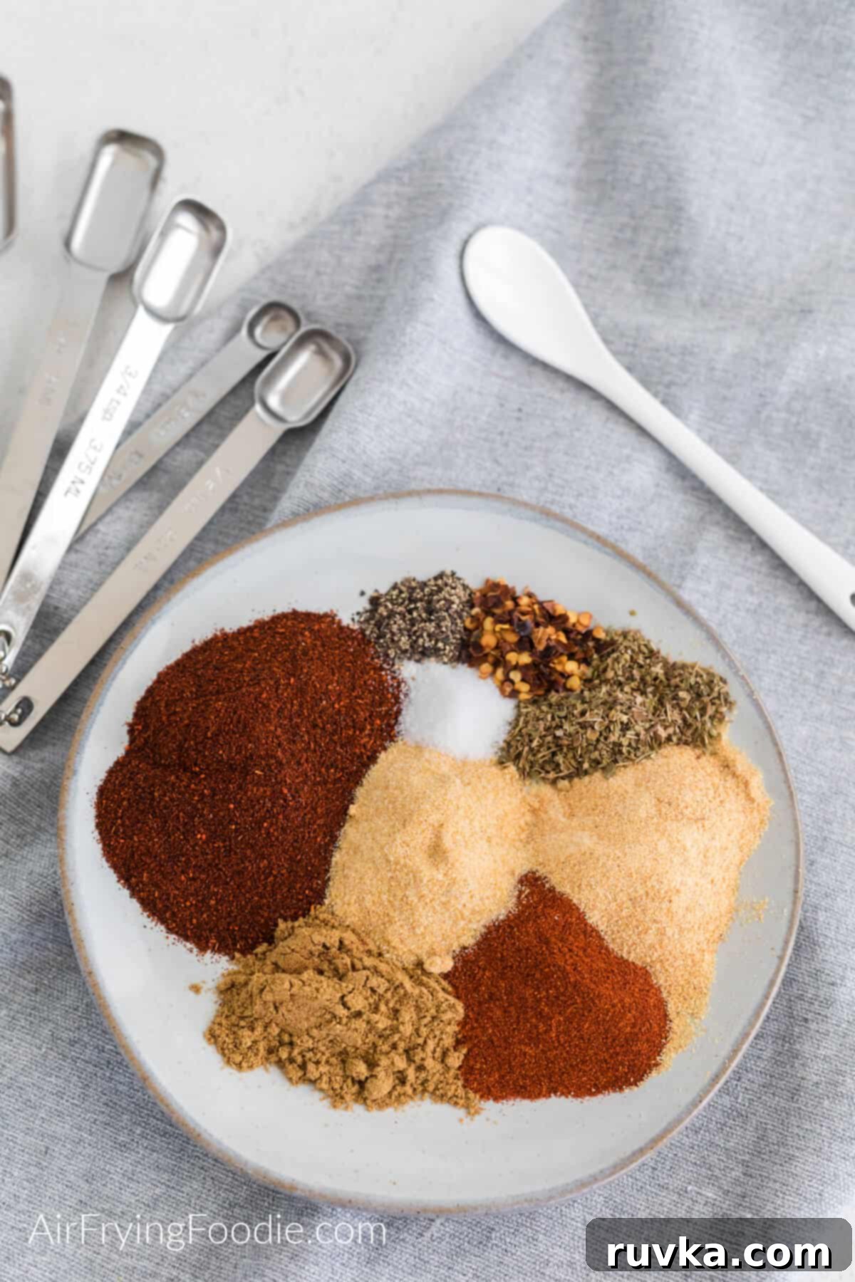 Craft Your Own Taco Spice Blend 5 Seasonings needed to make taco seasoning measured out on a plate, ready to be mixed together.