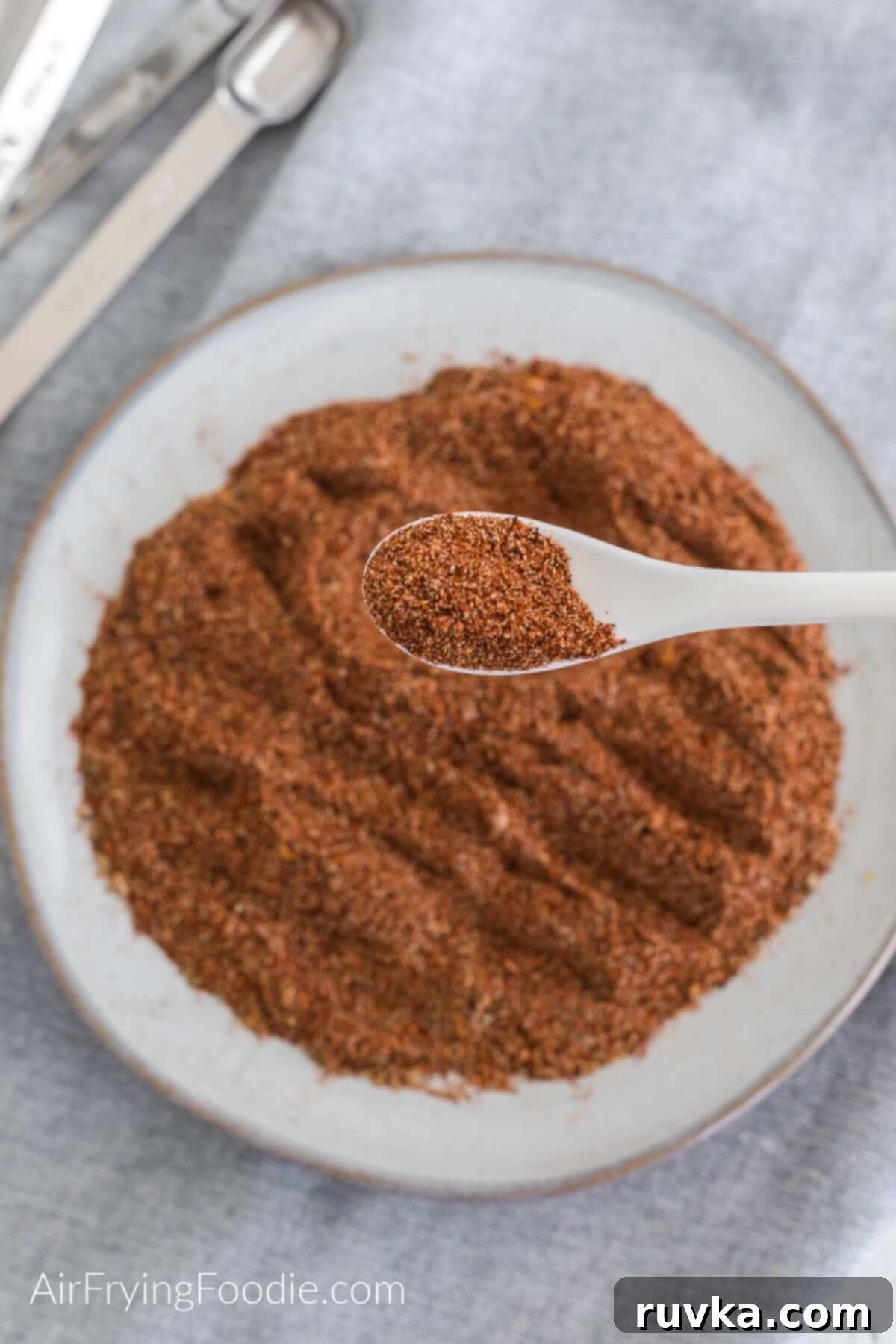 Craft Your Own Taco Spice Blend 7 Taco seasoning on a plate with a spoon full of the taco seasoning closer to the camera.