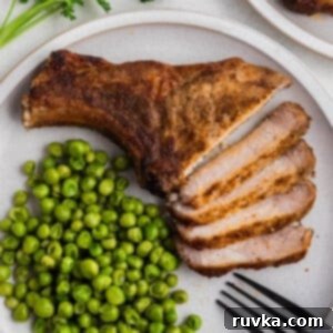 Delicious Air Fryer Pork Steaks 8 Air fried pork steak sliced and served on a plate with green peas.