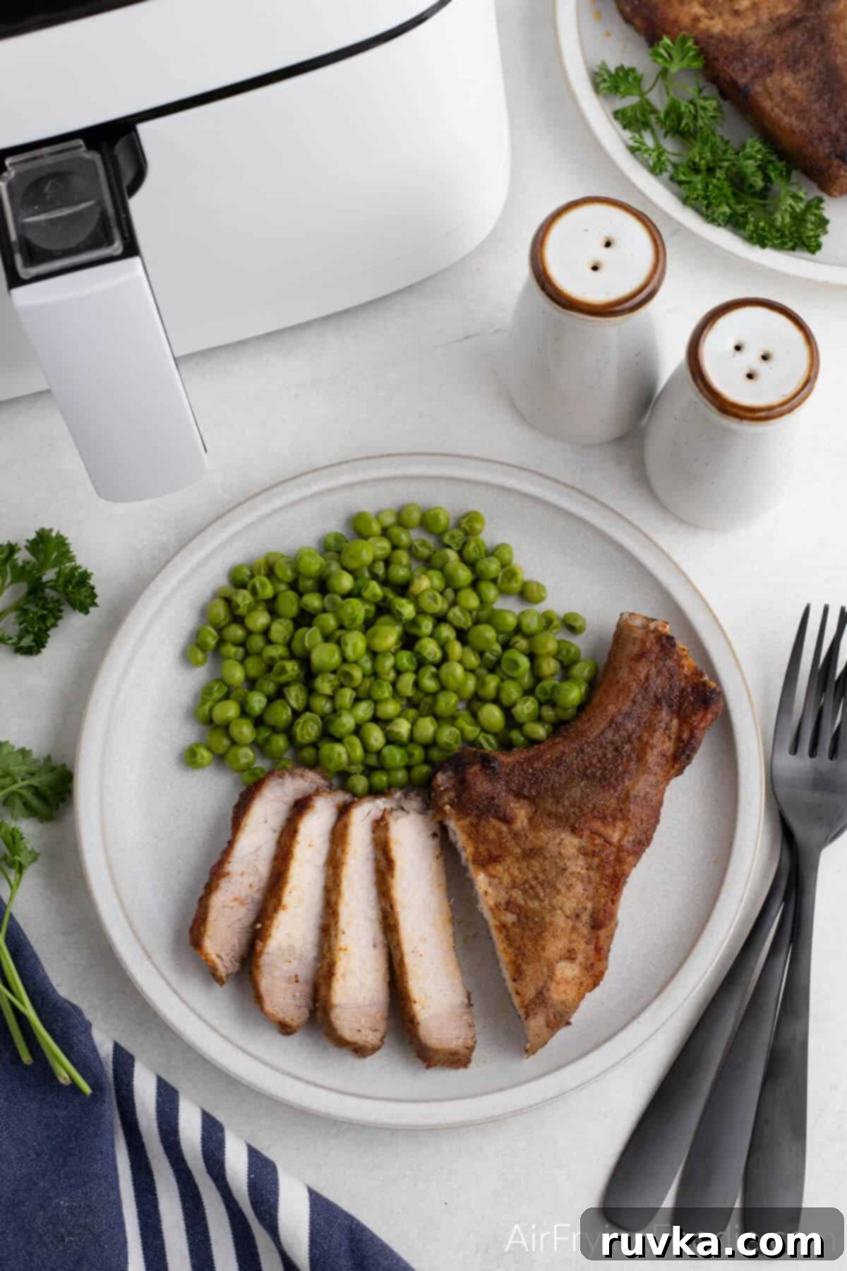 Delicious Air Fryer Pork Steaks 6 Overhead photo of pork steakmade in the air fryer, sliced and served with green peas.