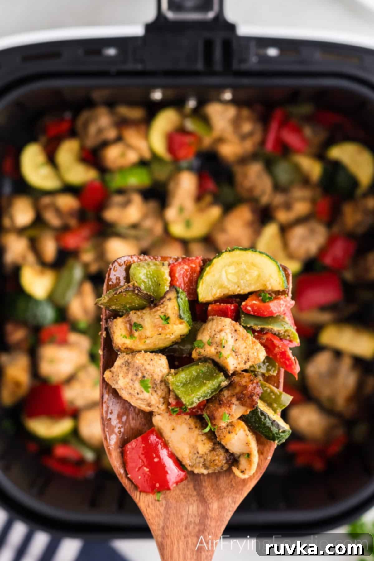 Crispy Air Fryer Chicken and Roasted Vegetables 4 air fried chicken and vegetables seasoned and held up over the basket of the air fryer.