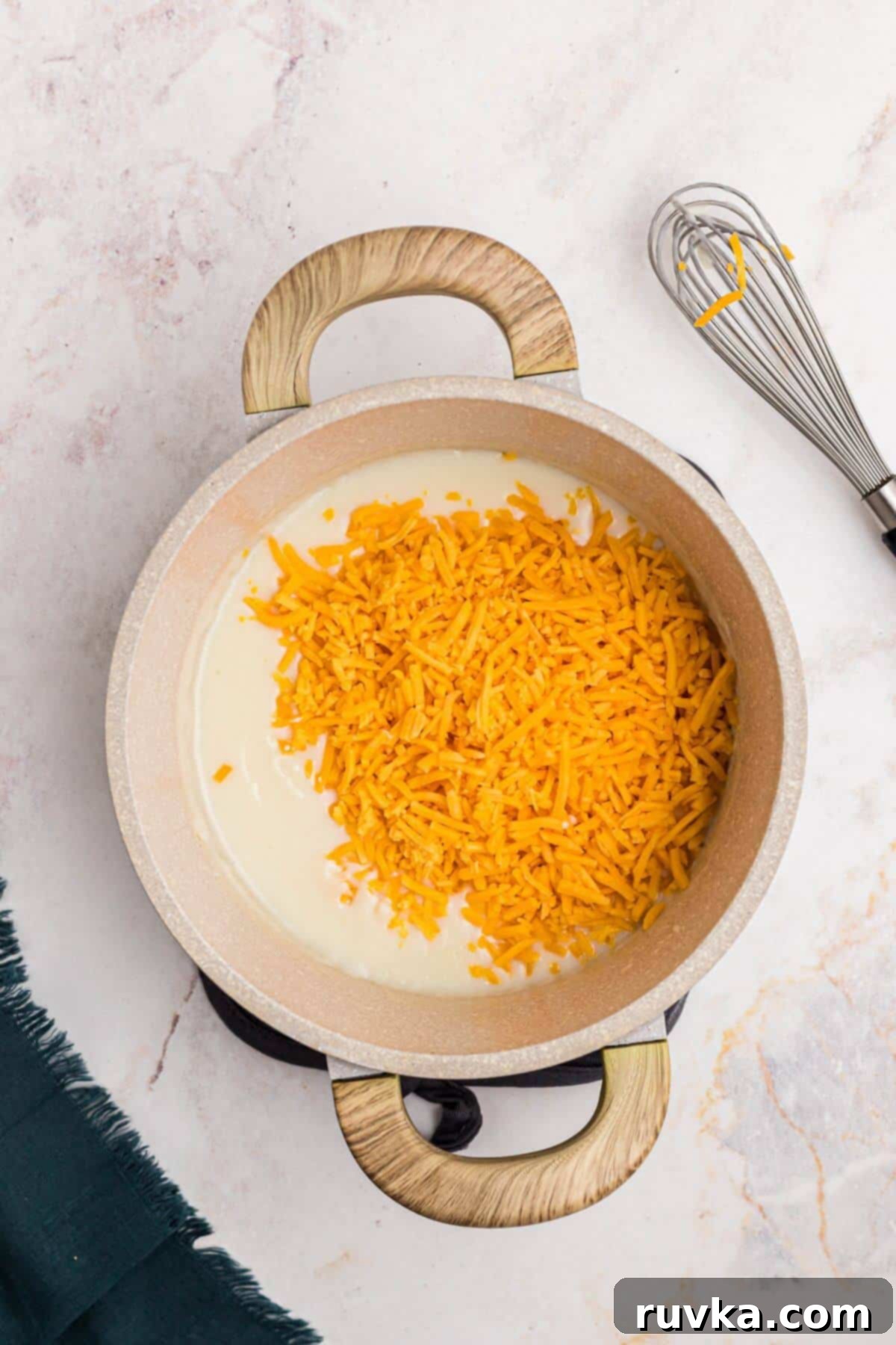 Creamy Cheese Sauce 6 Shredded cheddar cheese being added to the creamy mixture in a sauce pan.
