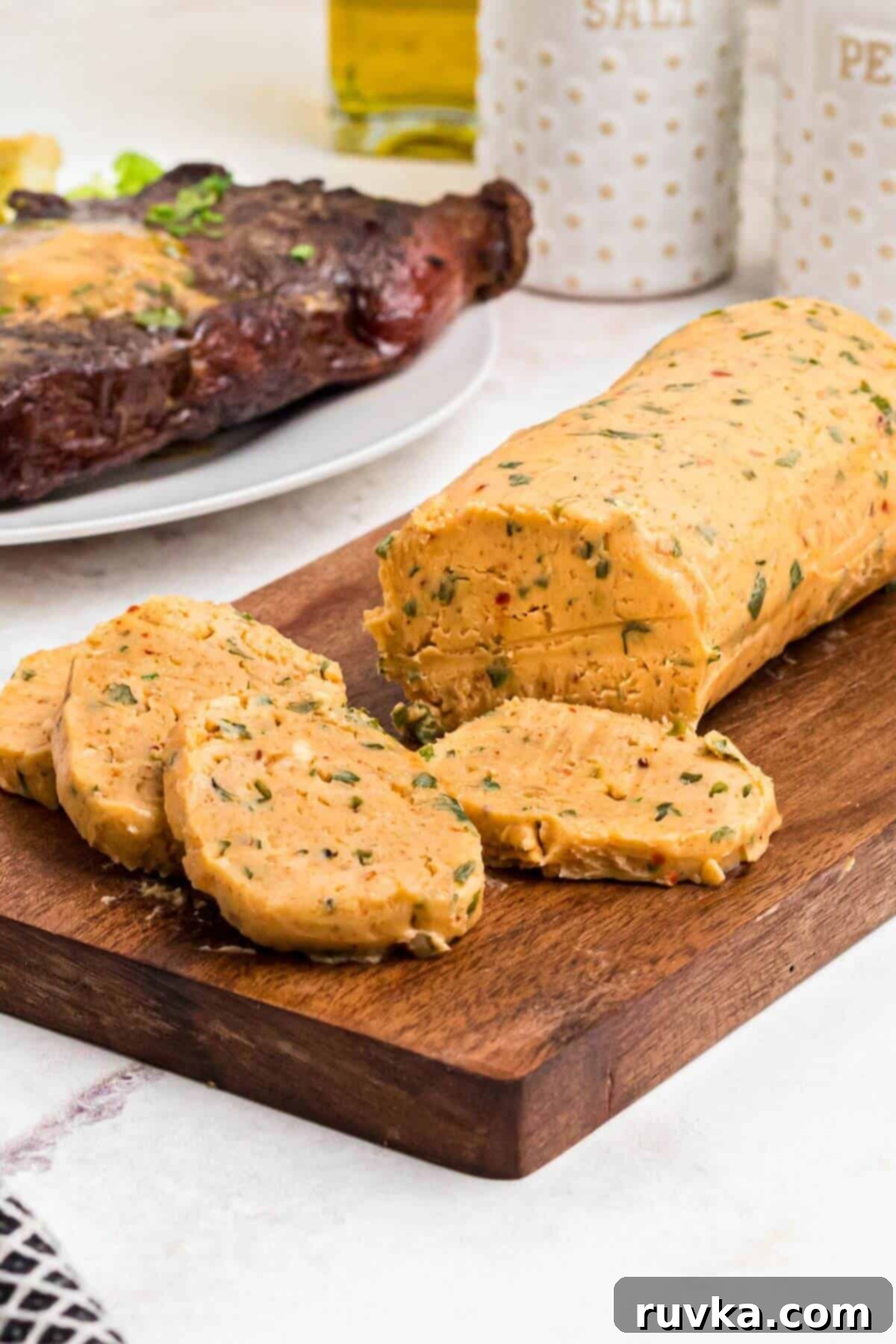 Robust Cowboy Butter 2 Golden seasoned butter in a roll and sliced on a small cutting board.