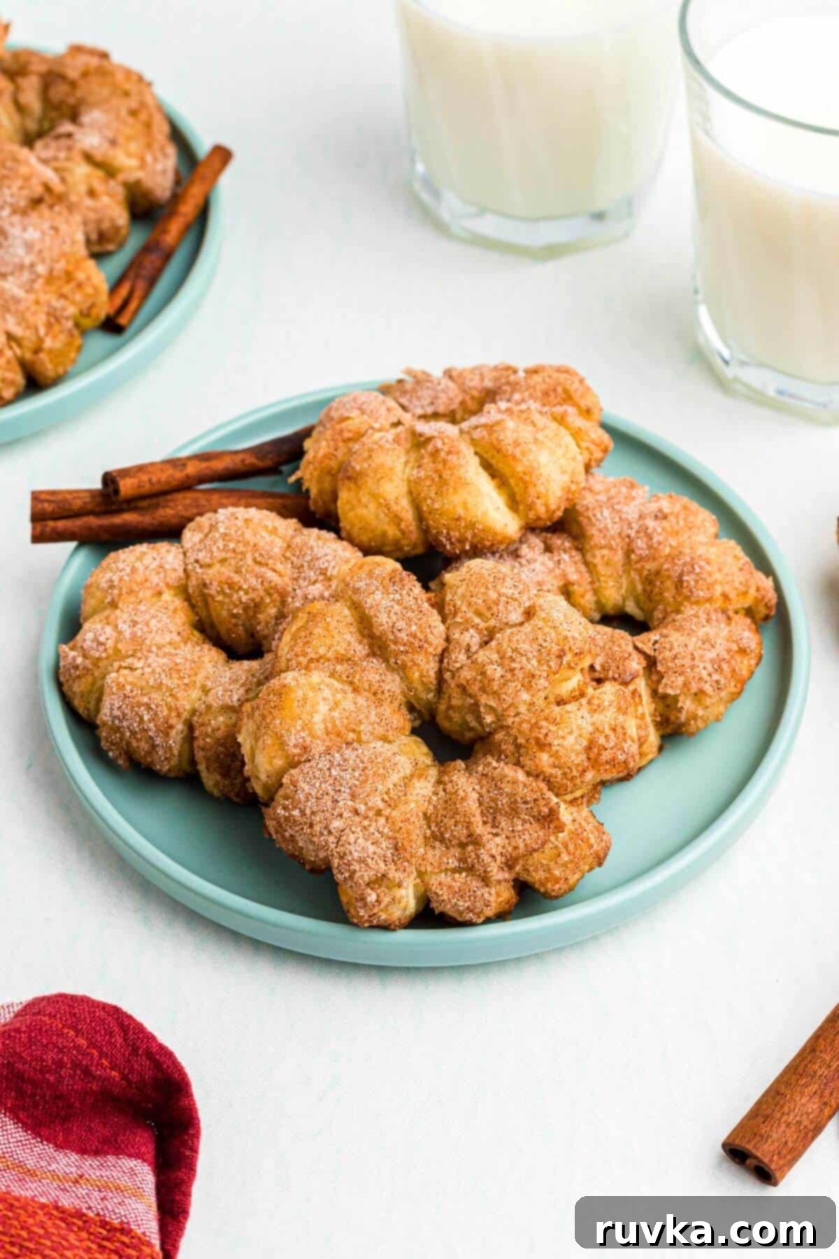 Flaky Air Fryer Apple Rings 2 Golden puff pastry wrapped apple rings that have been air fried and are on a light green plate.