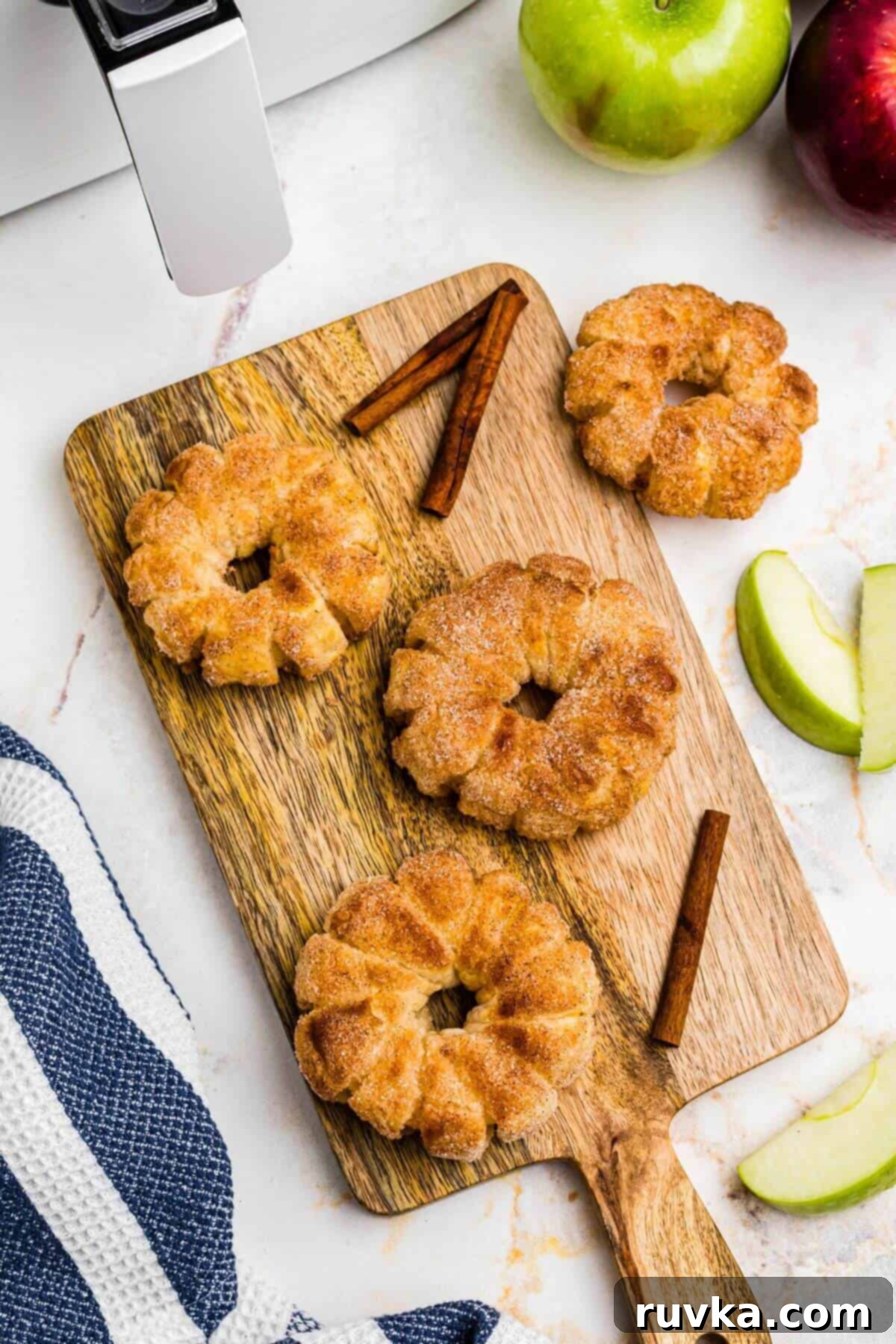 Flaky Air Fryer Apple Rings 11 Golden puff pastry wrapped apple rings on a cutting board with apple slices on the table.