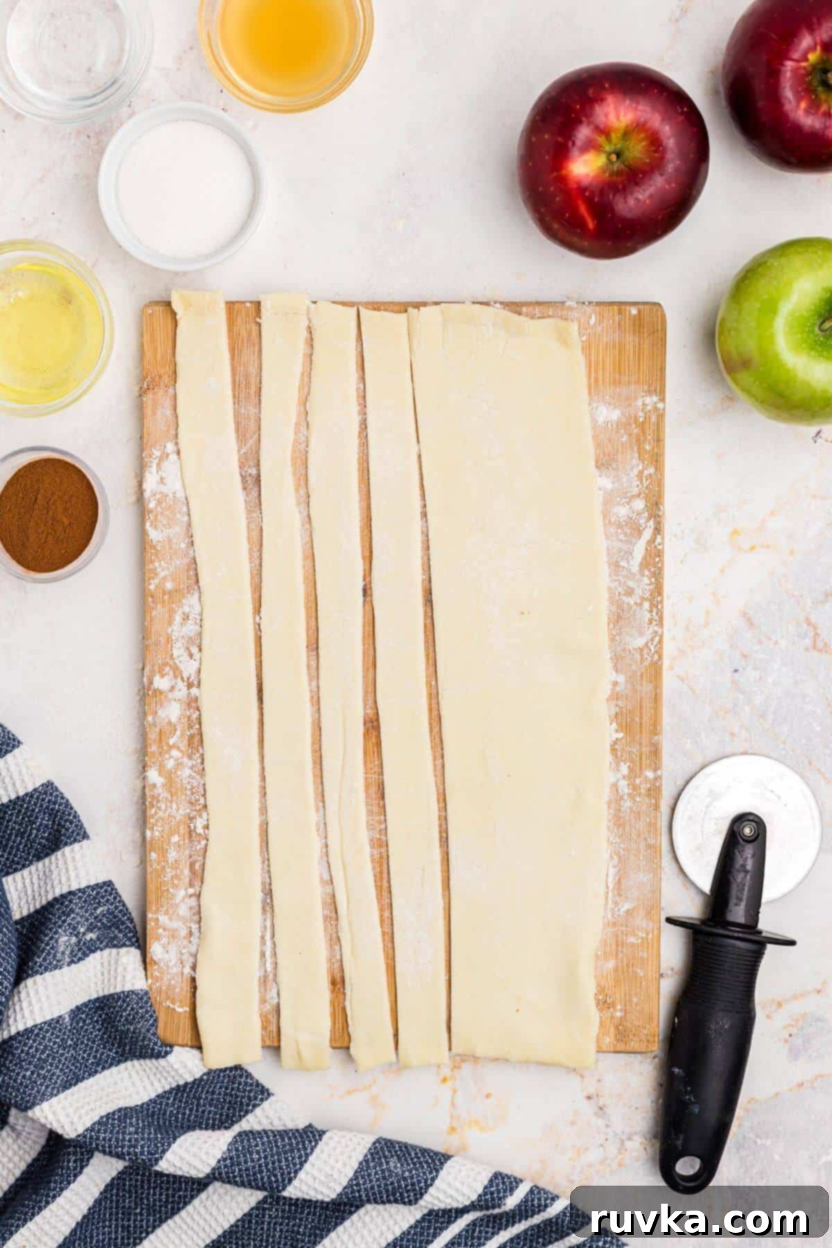 Flaky Air Fryer Apple Rings 4 Puff pastry sheet rolled out and cut into slices on a wooden cutting board.